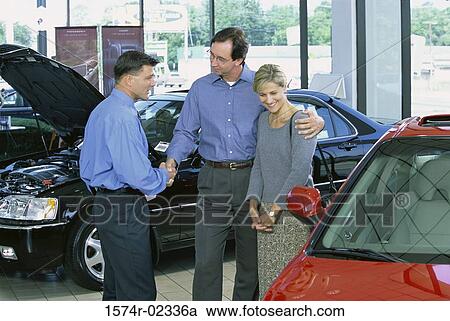Mid adult couple talking to a car salesman in a car showroom View Large Photo Image Stock Image - Mid adult couple talking to a car salesman in a car showroom. Fotosearch