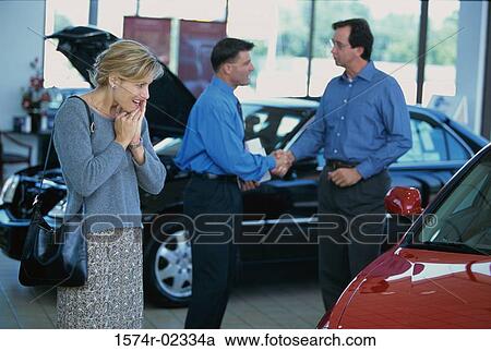Mid adult woman looking at a car in a car showroom View Large Photo Image Stock Image - Mid adult woman looking at a car in a car showroom. Fotosearch