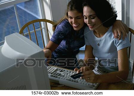 Stock Image - Mother and her daughter sitting in front of a computer. Fotosearch