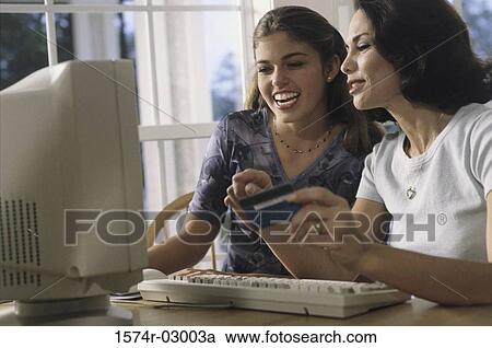 Mother and her daughter sitting in front of a computer View Large Photo Image Stock Image - Mother and her daughter sitting in front of a computer. Fotosearch