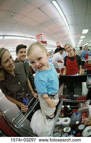 Stock Photo - Portrait of a baby boy standing on a shopping cart in a supermarket. Fotosearch