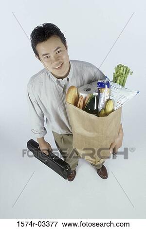 Portrait of a businessman holding a grocery bag and a briefcase View Large Photo Image Stock Photo - Portrait of a businessman holding a grocery bag and a briefcase. Fotosearch