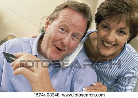 Stock Photo - Portrait of a mid adult couple holding a credit card. Fotosearch