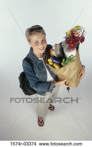 Portrait of a young woman carrying a grocery bag View Large Photo Image Picture - Portrait of a young woman carrying a grocery bag. Fotosearch