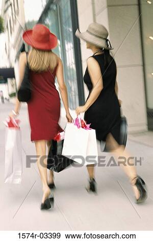 Stock Photo - Rear view of two young women carrying shopping bags. Fotosearch
