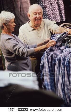 Stock Image - Senior couple choosing a shirt in a clothing store. Fotosearch