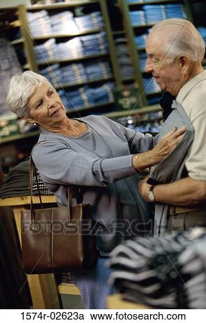 Stock Image - Senior woman holding a t-shirt against a senior man in a clothing store. Fotosearch