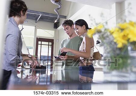 Stock Photography - Side profile of a young couple looking at a wallet in a store. Fotosearch