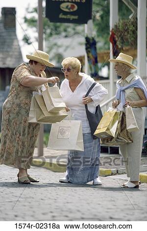 Stock Image - Three senior women walking with shopping bags. Fotosearch