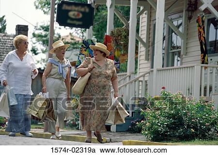 Stock Image - Three senior women walking with shopping bags. Fotosearch