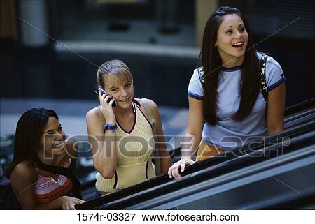 Three teenage girls standing on an escalator in a shopping mall View Large Photo Image Stock Photo - Three teenage girls standing on an escalator in a shopping mall. Fotosearch