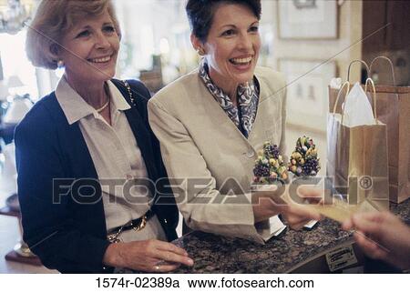Stock Image - Two mature women at a store counter. Fotosearch