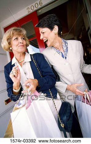 Two mature women carrying shopping bags View Large Photo Image Stock Image - Two mature women carrying shopping bags. Fotosearch
