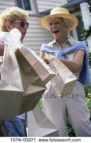 Two senior women carrying shopping bags View Large Photo Image Stock Image - Two senior women carrying shopping bags. Fotosearch