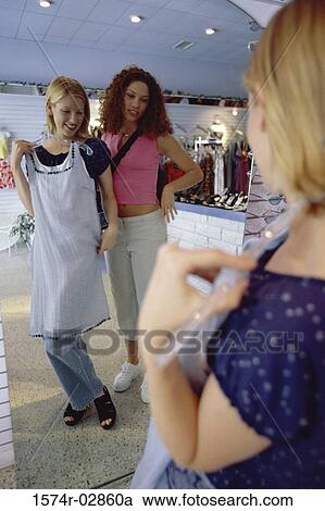 Two young women trying on clothes in a clothing store View Large Photo Image Stock Image - Two young women trying on clothes in a clothing store. Fotosearch