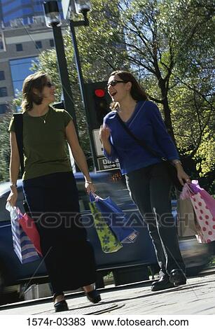 Stock Image - Two young women walking with shopping bags. Fotosearch