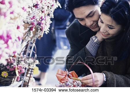 Young couple looking at flowers View Large Photo Image Picture - Young couple looking at flowers. Fotosearch