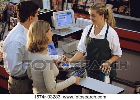 Stock Image - Young couple standing at the checkout counter in a supermarket. Fotosearch