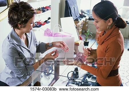 Stock Image - Young woman looking at jewelry in a store. Fotosearch