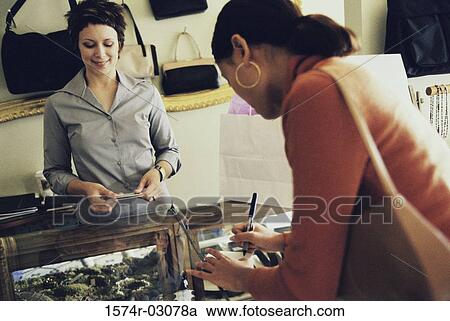 Stock Image - Young woman standing at a checkout counter. Fotosearch