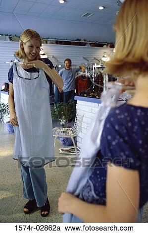 Stock Image - Young woman trying on clothes in a clothing store. Fotosearch