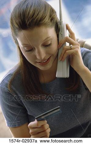 Young woman using a cordless phone holding a credit card View Large Photo Image Stock Image - Young woman using a cordless phone holding a credit card. Fotosearch