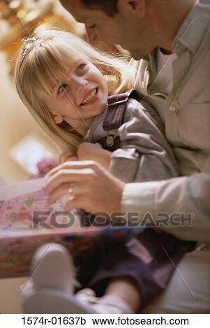 Stock Image - Close-up of a father reading to his daughter. Fotosearch