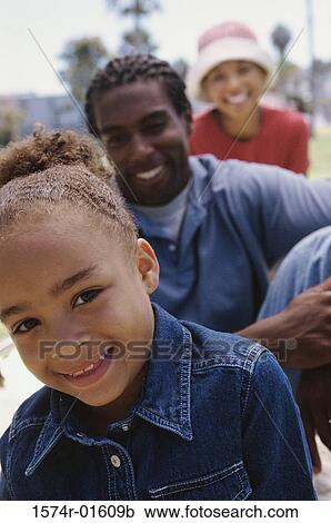 Close-up of a girl at the park with her parents View Large Photo Image Stock Image - Close-up of a girl at the park with her parents. Fotosearch