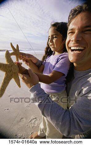 Close-up of a man showing his daughter a starfish on the beach View Large Photo Image Stock Image - Close-up of a man showing his daughter a starfish on the beach. Fotosearch