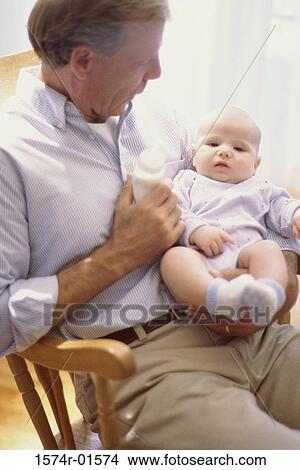 Picture - Close-up of a man sitting in a rocking chair with a baby. Fotosearch