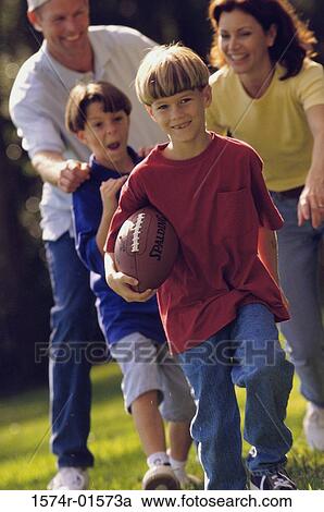 Couple playing football with their sons View Large Photo Image Stock Image - Couple playing football with their sons. Fotosearch