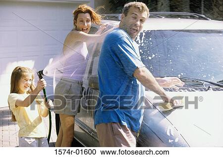 Stock Image - Daughter and her parents washing a car. Fotosearch