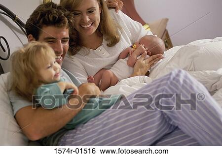 Daughter lying in bed with her parents View Large Photo Image Stock Photograph - Daughter lying in bed with her parents. Fotosearch