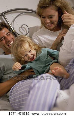 Daughter lying in bed with her parents View Large Photo Image Stock Photography - Daughter lying in bed with her parents. Fotosearch