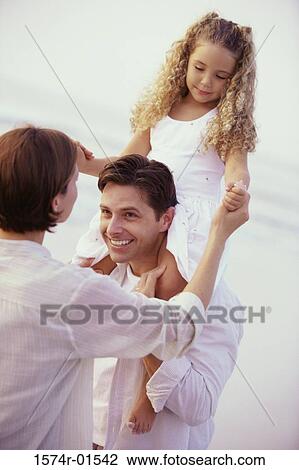 Stock Image - Daughter sitting on her father's shoulders. Fotosearch