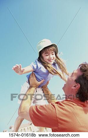 Stock Image - Daughter thrown up in the air by her father. Fotosearch