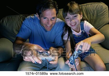 Stock Image - Father and daughter playing a video game together. Fotosearch