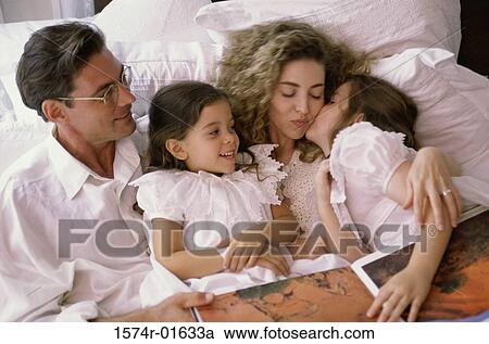 Father and mother lying in bed with their two daughters View Large Photo Image Stock Image - Father and mother lying in bed with their two daughters. Fotosearch