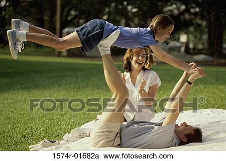 Father and mother playing with their daughter on a lawn View Large Photo Image Stock Image - Father and mother playing with their daughter on a lawn. Fotosearch