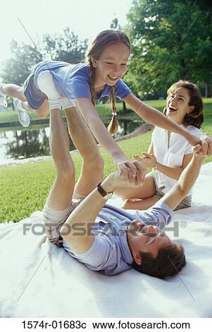 Father and mother playing with their daughter on a lawn View Large Photo Image Stock Image - Father and mother playing with their daughter on a lawn. Fotosearch