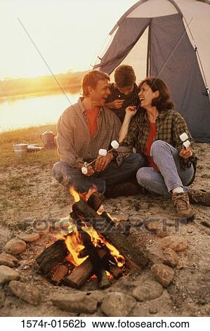 Stock Image - Father and mother with their son in front of a campfire on the beach. Fotosearch