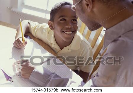 Stock Image - High angle view of a father tutoring his son. Fotosearch