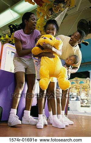Stock Image - Low angle view of a couple in an amusement park with their son and daughter. Fotosearch