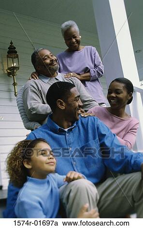 Stock Image - Low angle view of a family sitting on the front porch together. Fotosearch
