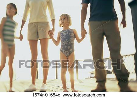 Stock Image - Low angle view of a mother and father standing with their two daughters. Fotosearch
