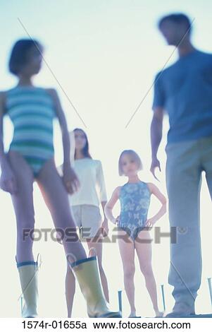 Stock Image - Low angle view of a mother and father standing with their two daughters. Fotosearch