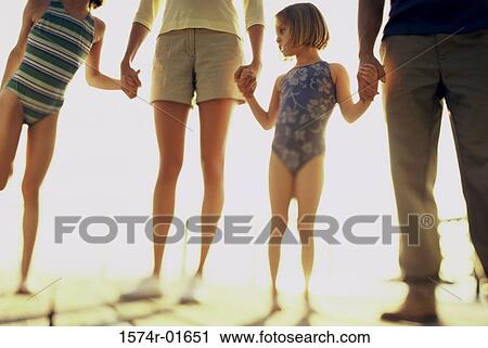 Low section view of a girl holding her parents hands standing at the beach View Large Photo Image Stock Image - Low section view of a girl holding her parents hands standing at the beach. Fotosearch