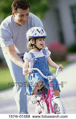 Man helping his daughter learn to ride a bicycle View Large Photo Image Stock Photo - Man helping his daughter learn to ride a bicycle. Fotosearch