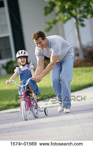 Man teaching his daughter to cycle View Large Photo Image Stock Photo - Man teaching his daughter to cycle. Fotosearch