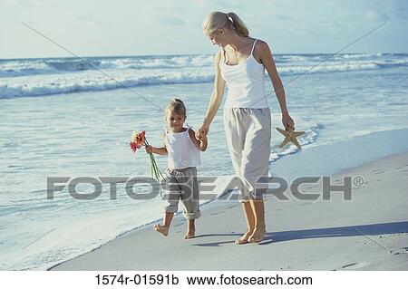 Stock Image - Mother and daughter walking on the beach. Fotosearch